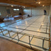 Basement renovation: white floor insulation panels, metal electrical conduit grid system, and worker.