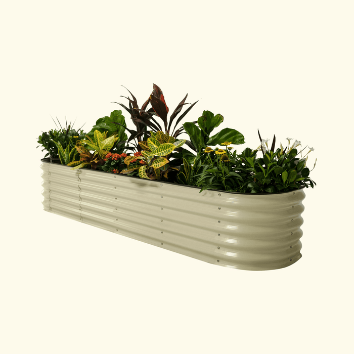 Long beige corrugated metal raised garden bed with diverse green plants, colorful foliage, and white/yellow flowers.