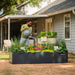 Man watering colorful flowers in a large black raised garden bed. Perfect for backyard gardening & outdoor planters.