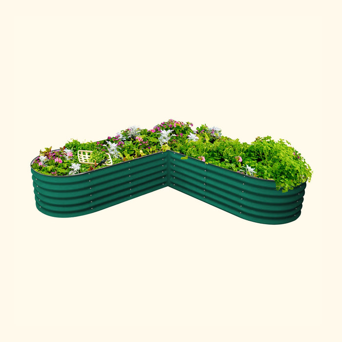 Green corrugated metal V-shaped raised garden bed filled with lush herbs, vegetables, and colorful flowers.