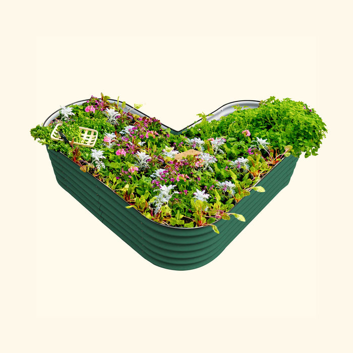 Green heart-shaped corrugated metal raised garden bed with vibrant vegetables, herbs, and colorful flowers.