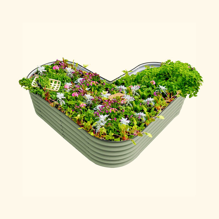 Sage green heart-shaped metal raised garden bed brimming with colorful flowers, fresh herbs, and leafy greens.