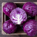 Five fresh red cabbage heads, one cut in half, in a wooden crate. Vibrant purple vegetable for healthy meals.