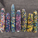 Seven vibrant multicolor heirloom corn cobs (Glass Gem maize) on rustic wood.