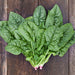 Fresh green spinach bundles on a dark rustic wooden background. Healthy leafy greens vegetable.