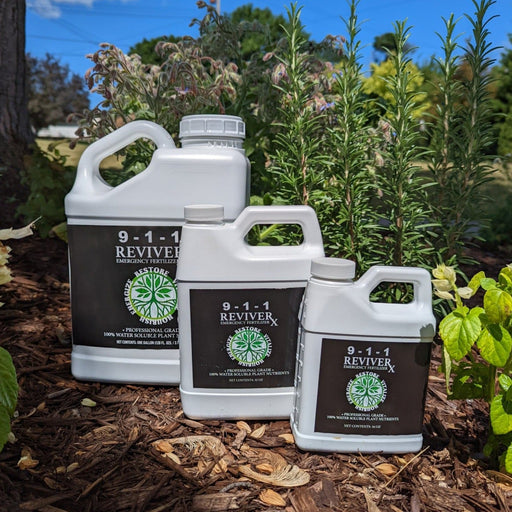 Three 9-1-1 Reviver Emergency Fertilizer bottles on garden mulch. Professional grade, water soluble plant nutrients for vibrant plants.