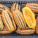 Fresh spaghetti squash, whole and cut open with seeds, in a black crate. Healthy winter squash harvest.