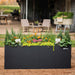 Vego Garden black metal raised planter box with marigolds, cyclamen, and various green plants on a patio.