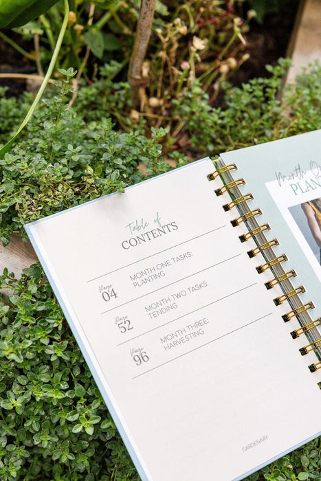 Gardenary gardening planner open to Table of Contents with planting, tending, harvesting tasks. Gold spiral, green plants.