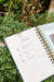 Gardenary gardening planner open to Table of Contents with planting, tending, harvesting tasks. Gold spiral, green plants.