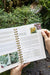 Open gardening book showing "Winter Sow Flowers" page with Black-Eyed Susans, Coneflowers, and broccoli in a garden.