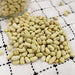 Pale green dried beans with black eyes scattered on a white checkered tablecloth. Healthy protein source, legumes.
