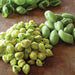 Fresh green garbanzo beans: shelled chickpeas and fuzzy pods on a rustic wooden board.