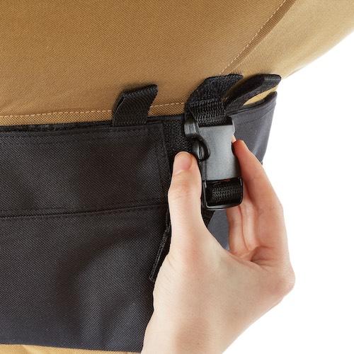 Hand securing a black quick-release buckle on a tan and black fabric strap. Durable closure for bags, covers, gear.