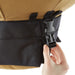Hand adjusting black plastic buckle on a rugged tan & black backpack. Secure strap for outdoor gear.