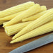 Fresh baby corn on a wooden cutting board with a knife. Healthy vegetable ingredient for stir-fries and cooking.