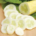 Fresh white cucumber, whole and thinly sliced, revealing seeds, on a cutting board with green leaves. Salad ingredient.