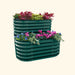 Two-tier dark green corrugated metal raised garden bed with diverse plants, vibrant red foliage, pink cyclamen, and blue pansies.