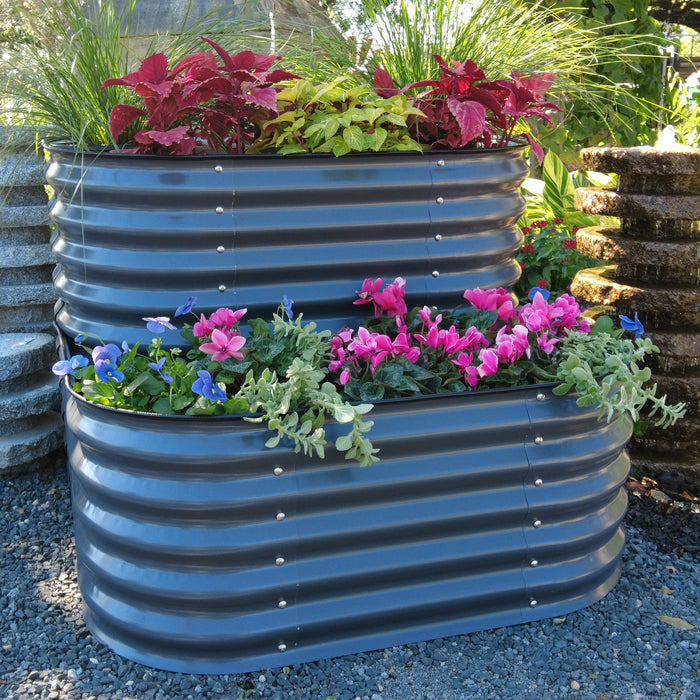 Tiered dark gray corrugated steel raised garden bed with vibrant coleus, cyclamen, pansies, and ornamental grass.