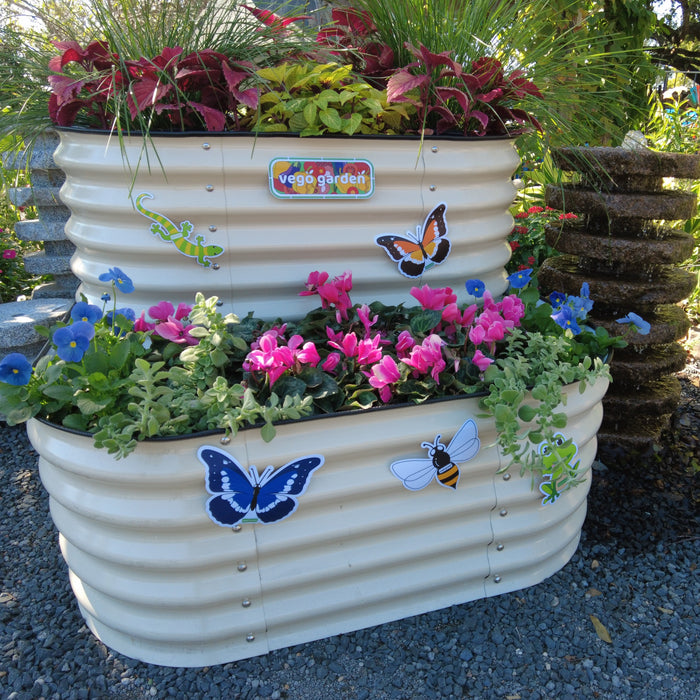 Vego Garden tiered corrugated metal raised garden bed with pink cyclamen, blue pansies, coleus, and animal stickers. Stone fountain.