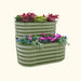 Olive green corrugated steel L-shaped two-tier raised garden bed with vibrant flowers and plants.