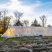 Large plastic hoop house greenhouse on a farm field. Sunlight illuminates plants inside for season extension farming.