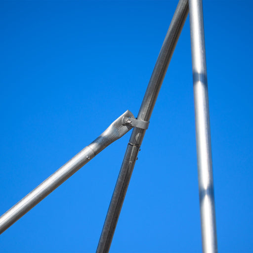 Galvanized steel structural pipes joined by a metal clamp and bolt against a clear blue sky.
