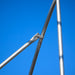Galvanized steel structural pipes joined by a metal clamp and bolt against a clear blue sky.