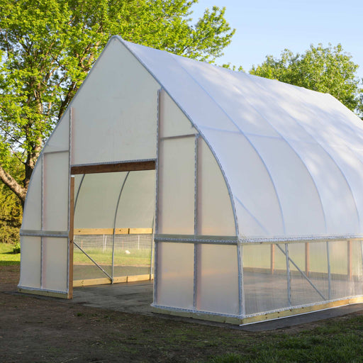 Large hoop house greenhouse with translucent plastic, wooden frame, and open doorway. Ideal for extended season gardening.