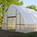 Large hoop house greenhouse with translucent plastic, wooden frame, and open doorway. Ideal for extended season gardening.