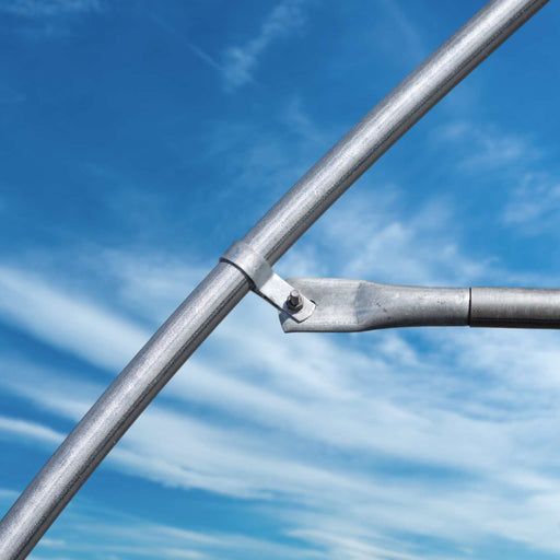 Galvanized steel pipe fitting with clamp and bolt for structural support against a sunny blue sky.