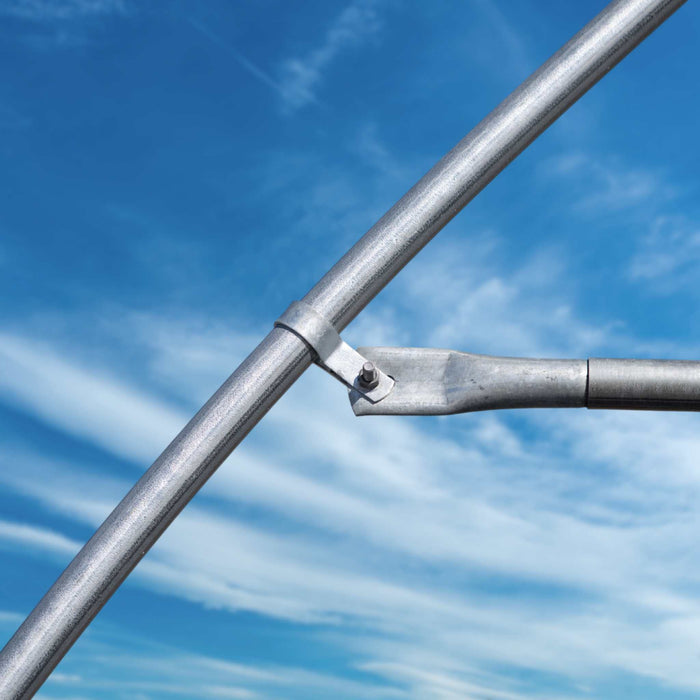 Galvanized steel pipe fitting with clamp and bolt for structural support against a sunny blue sky.
