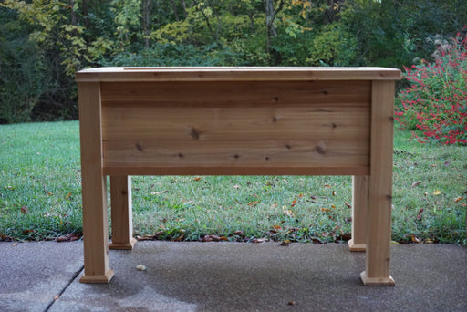 Elevated wooden planter box for outdoor gardening. Sturdy natural wood raised garden bed on a patio.