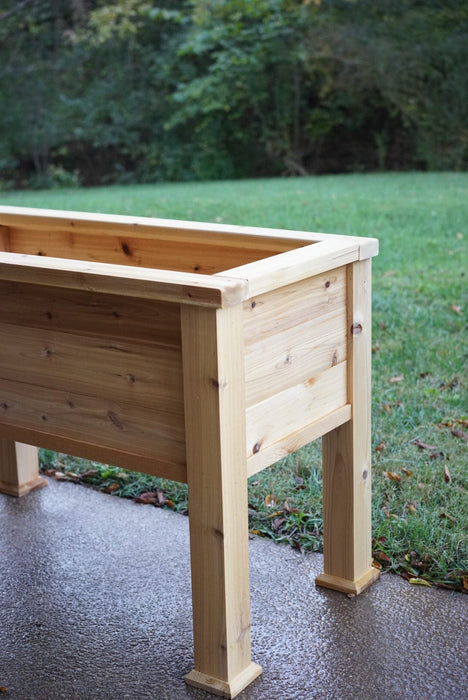 Cedar raised garden planter box on a wet patio, ideal for herbs, vegetables, and flowers.