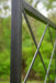 Textured black metal fence post and lattice design with blurred green foliage. Modern outdoor garden fencing.