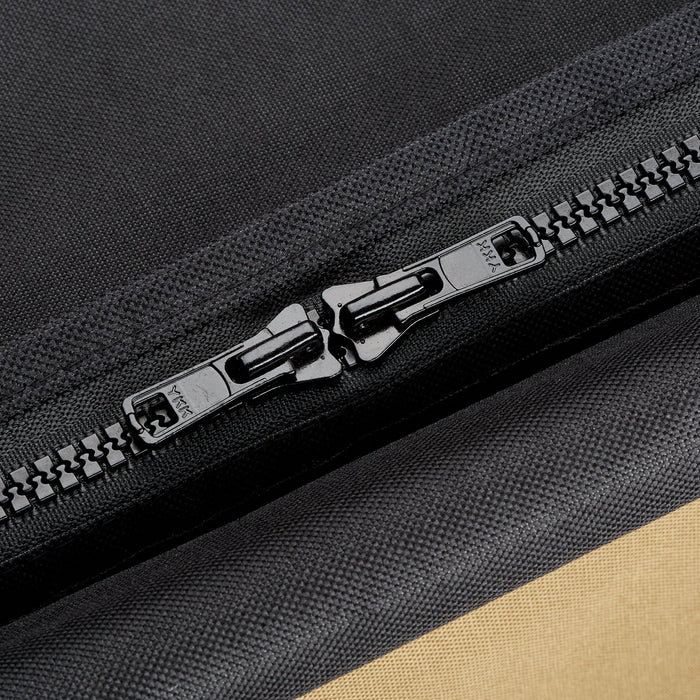 Black YKK zipper with dual pulls on textured black fabric, revealing a tan section. Durable textile and gear detail.