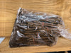 Plastic bag of dormant woody plant cuttings, bundled with red ties and moist soil, on a textured wooden background. For propagation.