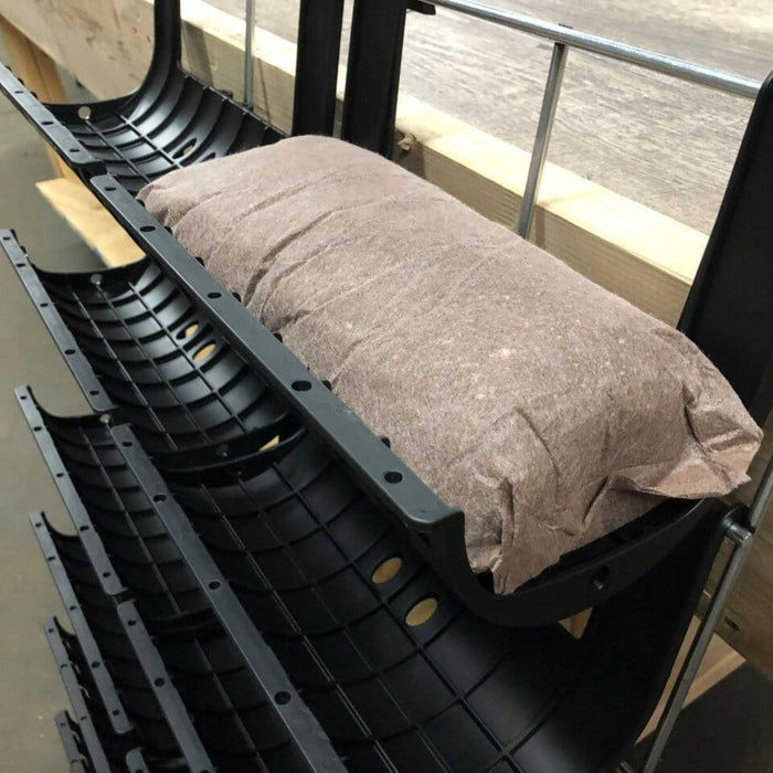 Black plastic industrial channels with a brown absorbent filter sock for environmental spill control and fluid management.