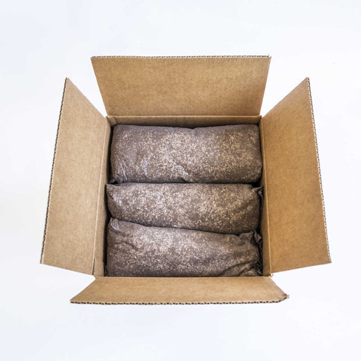 Open cardboard shipping box with three packed bags of granular soil, compost, or growing medium for plants.