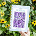 "Hot Season" gardening planner by Gardenary, featuring striped eggplants, held amidst yellow Black-eyed Susan flowers.