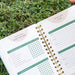 Weekly garden planner open to habit tracker and goals, featuring indoor gardening tasks like sprouts and microgreens, on green plants.
