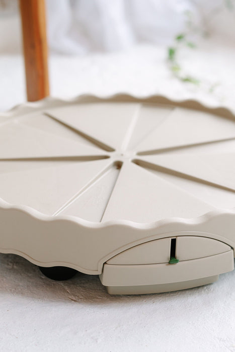 Beige plastic pie carrier base with 8 slice dividers, wavy edge, and green locking latch. Portable dessert transport.