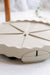 Beige plastic pie carrier base with 8 slice dividers, wavy edge, and green locking latch. Portable dessert transport.