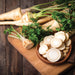 Fresh whole and sliced parsnips with green tops on a rustic wooden board. Healthy root vegetables.