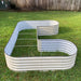 Outdoor L-shaped light grey corrugated steel raised garden bed with internal support rods on green grass.