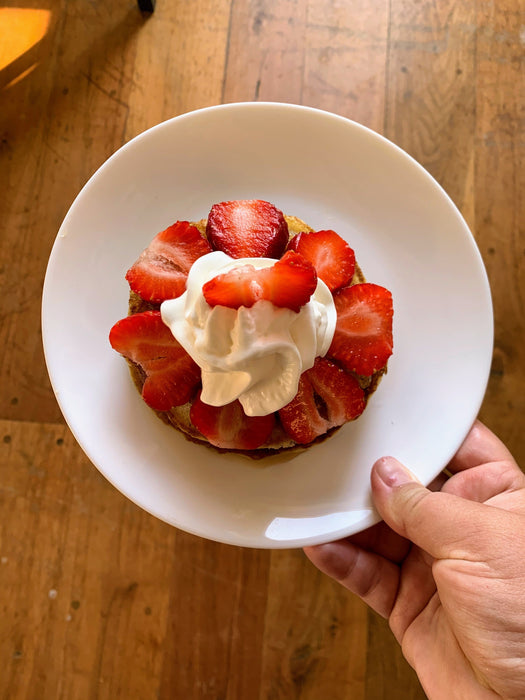 Golden pancake topped with fresh sliced strawberries and whipped cream. Delicious breakfast dessert.