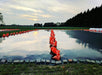 Farm field with black plastic mulch secured by orange sandbags, bricks, reflecting sunset. Crop growing.
