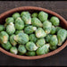 Abundance of fresh green Brussels sprouts in a woven basket on a dark wooden surface. Healthy, organic produce.