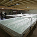 Commercial indoor aquaculture facility with large water pools, bright grow lights, and two men observing.