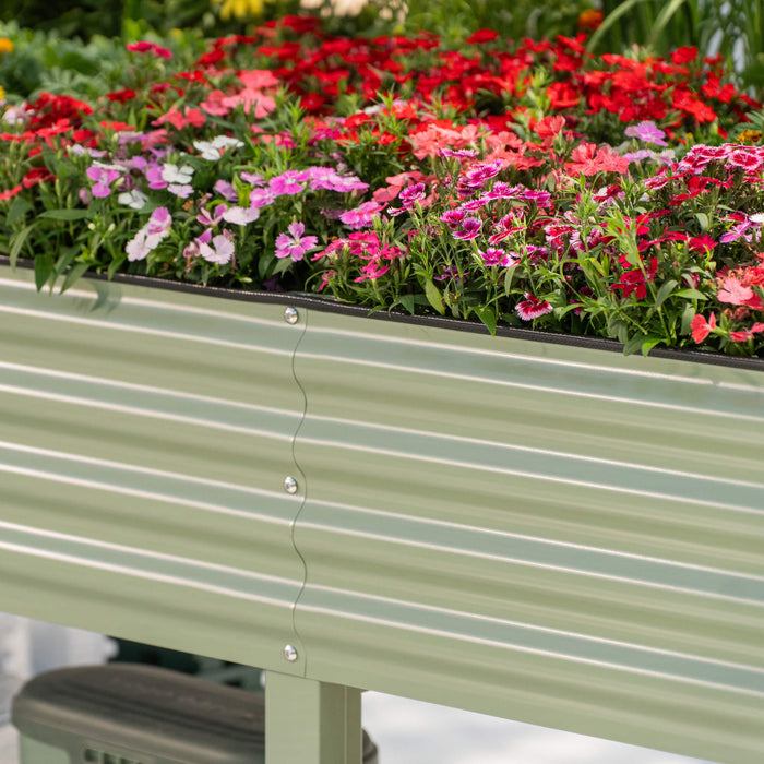 Sage green corrugated raised garden bed with vibrant red, pink, and purple Dianthus flowers.